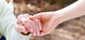 Zdjęcie przedstawia dwie dłonie starszej i młodej osoby